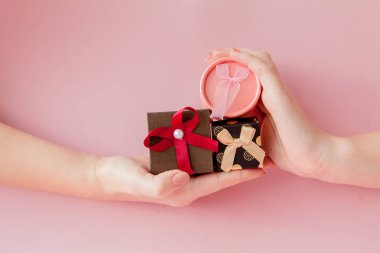 Kadınların elleri pembe bir arka plan üzerinde küçük hediye kutuları. Sevgililer günü, anneler günü veya Doğum günü için festival kavramı.