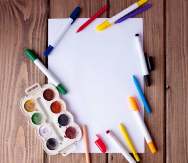 Beyaz kağıdın bir ahşap, yakın, kurşun kalem, boya ve işaretleri açayım. Okula dönüş. okul ve ofis malzemeleri. Eğitim ve okul kavramı ve kopya alanı ahşap arka plan üzerinde kenarlık.