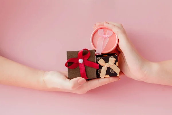 Small gift boxes in women\'s hands on a pink background. Festive concept for Valentine\'s day, Mother\'s day or birthday.