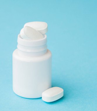 Hap hap şişesi üzerinde mavi arka plan dışarı dökülmesini kapatın. Tıp, sağlık sigortası veya eczane konsepti.