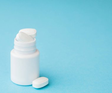 Hap hap şişesi üzerinde mavi arka plan dışarı dökülmesini kapatın. Tıp, sağlık sigortası veya eczane konsepti.