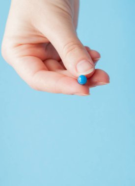Yakın çekim kapsül üzerinde mavi arka plan izole hemşirenin elinde kadeh.