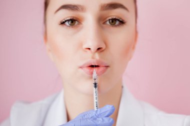 Bir şırınga için enjeksiyon, pembe bir arka plan üzerinde tutan hemşire kapatın.