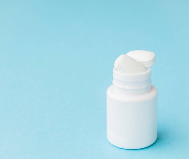 Hap hap şişesi üzerinde mavi arka plan dışarı dökülmesini kapatın. Tıp, sağlık sigortası veya eczane konsepti.