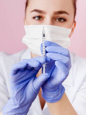 Bir şırınga için enjeksiyon, pembe bir arka plan üzerinde tutan hemşire kapatın.