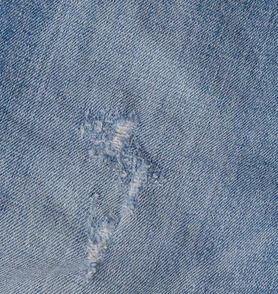 Gat en Threads op Denim Jeans. Geripte vernietigd verscheurd blauw jeans achtergrond. Close-up van blauwe jean textuur — Stockfoto