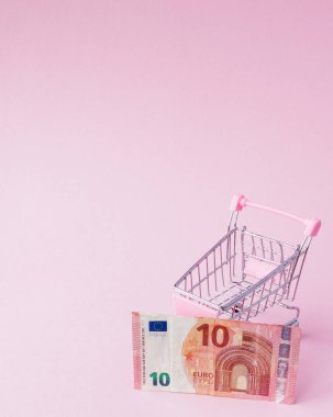 Süpermarket arabası tam Euro banknot kopya alanı ile pembe bir arka plan üzerinde. Serbest ticaret. para piyasası. Minimalizm tarzı. Süpermarkette alışveriş arabası. Satış, iskonto.