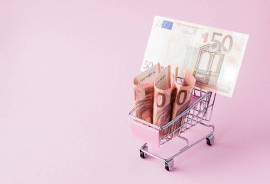 Süpermarket arabası tam Euro banknot kopya alanı ile pembe bir arka plan üzerinde. Serbest ticaret. para piyasası. Minimalizm tarzı. Süpermarkette alışveriş arabası. Satış, iskonto.