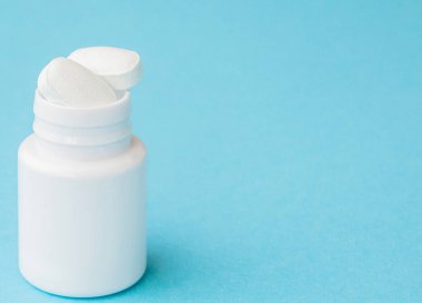 Hap hap şişesi üzerinde mavi arka plan dışarı dökülmesini kapatın. Tıp, sağlık sigortası veya eczane konsepti.