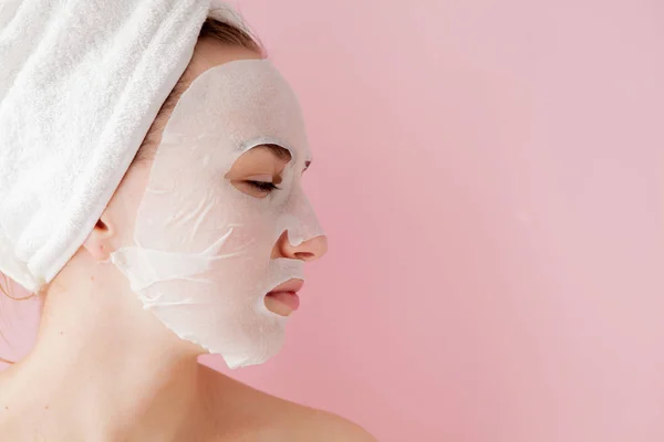 Krásná Mladá Žena Použití Kosmetických Tkáně Masku Obličej Růžovém Pozadí — Stock fotografie