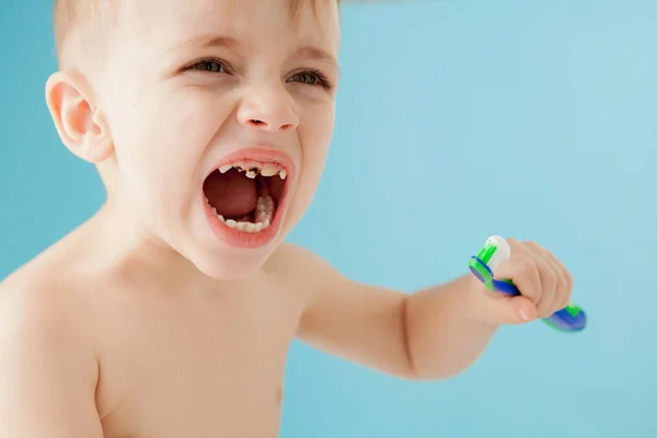 Retrato de niño pequeño con cepillo de dientes sobre fondo azul — Foto de Stock