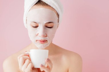 Bornozlu güzel bir kızın portresi bir fincan çay, gevşeme konsepti bornoz giyen sarışın kadın ve duş üstüne havlu. Bornoz ve türbanlı spa kadını