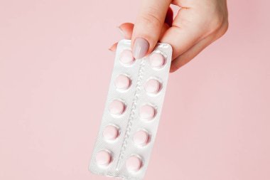 Kadının elinde pembe bir arka plan üzerinde pembe hap paketi. Üstten Görünüm. Düz yatıyordu. Uzay kopyalayın. Tıp kavramı.