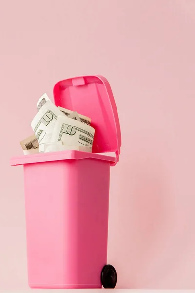 Dollar biljetten in roze vuilnisbak op roze achtergrond — Stockfoto