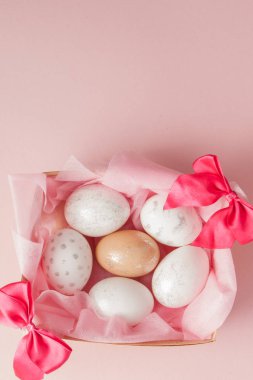 Paskalya yumurtaları bir yuvaya pembe bir arka plan üzerinde beyaz. Tasarım pastel tonda en az düz lay