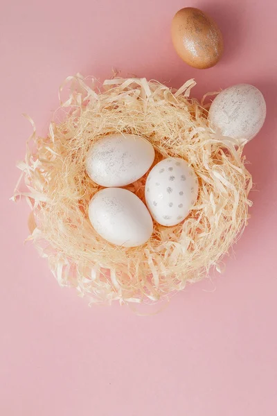 Huevos blancos de Pascua en un nido sobre fondo rosa. Diseño de tono pastel en la posición plana mínima — Foto de Stock