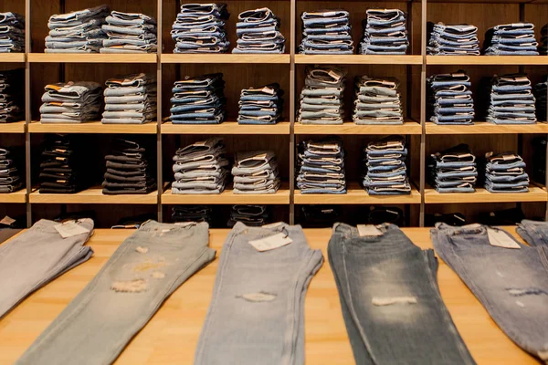 Pantalones vaqueros en el estante de la tienda. Azul jeans denim colección jeans apilados — Foto de Stock