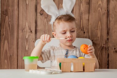 Küçük çocuk renkli yumurta Paskalya için ahşap arka plan üzerinde boyama