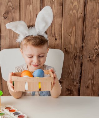 Küçük çocuk renkli yumurta Paskalya için ahşap arka plan üzerinde boyama