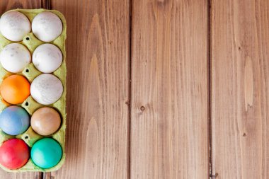 Kutusunda kopya alanı ile ahşap arka plan üzerinde renkli Paskalya yumurtaları