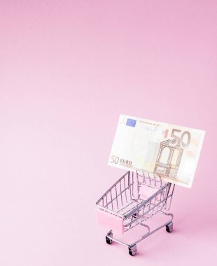 Süpermarket arabası tam Euro banknot kopya alanı ile pembe bir arka plan üzerinde. Serbest ticaret. para piyasası. Minimalizm tarzı. Süpermarkette alışveriş arabası. Satış, iskonto