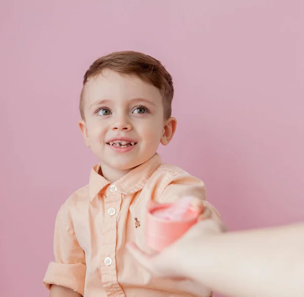 Bir hediye ile mutlu küçük çocuk. Fotoğraf, pembe arka plan izole. Boy gülümseyerek mevcut kutusu tutar. Kavramı tatil ve Doğum günü — Stok fotoğraf