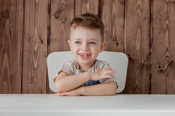 Um menino bonito está sentado à mesa. Close-up — Fotografia de Stock
