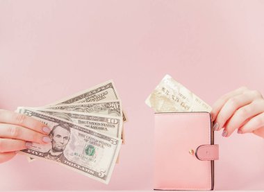 Kiev, Ukrayna - 22 Şubat 2019: Dolar ve kadının elinde pembe bir arka plan üzerinde kredi kartıyla pembe cüzdan