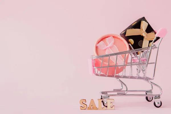 Online shopping concept, uw winkelwagen met geschenk dozen op roze achtergrond met kopie ruimte — Stockfoto