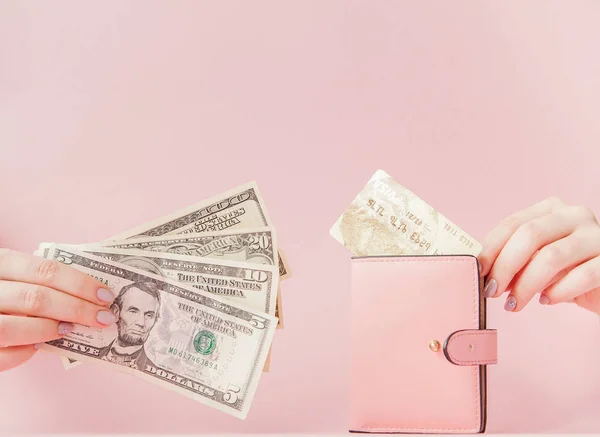 Kiev, Ucrânia - 22 de fevereiro de 2019: Dólares e carteira rosa com cartão de crédito nas mãos da mulher sobre fundo rosa — Fotografia de Stock