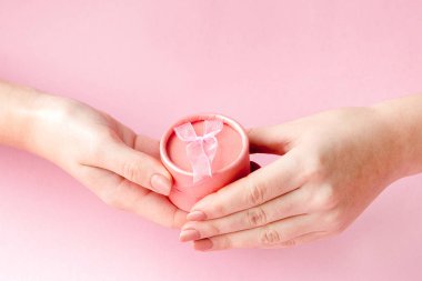 Pembe bir arka planda kadınların ellerinde yuvarlak pembe hediye kutusu. Festi