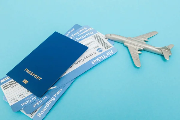 Tickets for plane and passport with model of plane on blue backg