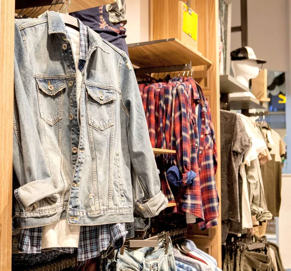 Pantalones cortos, camisetas, camisetas y chaqueta en el estante de la tienda. Ropa de moda en los estantes de la tienda. Escaparate, venta, compras. Lujo y nuevo interior de moda de la tienda de tela — Foto de Stock