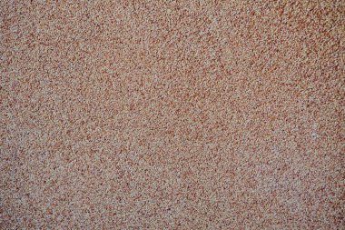 Yayılmış kum taneciklerinin arka planında bir taş kırıntısı var. Bir duvarın yüzeyinin dokusu, açık renk