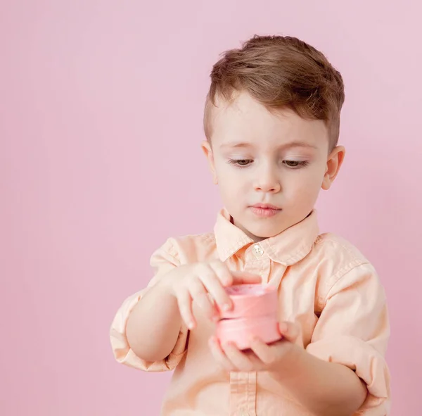 Um rapazinho feliz com um dom. Foto isolada em fundo rosa — Fotografia de Stock