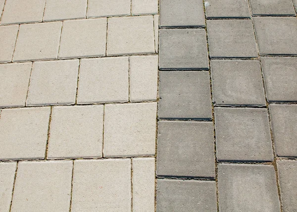 黒とグレーの石畳の歩道は、幾何学模様に敷かれています。彼らは時間で着用します。 — ストック写真