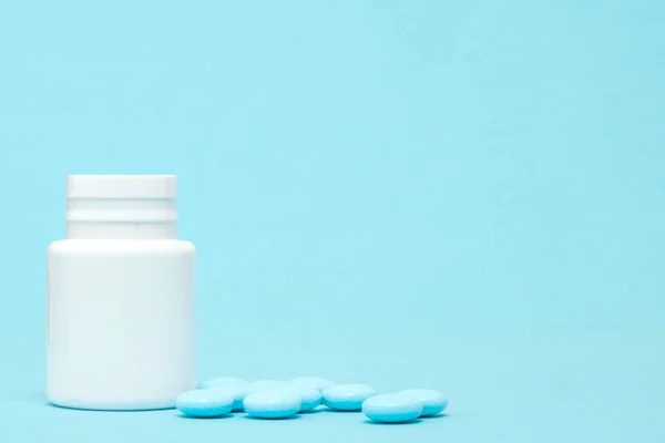Blaue Pillen und Tablettenflasche auf blauem Hintergrund — Stockfoto