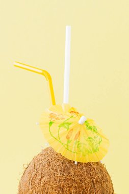 Sarı arka planda bir pipet ile taze Hindistan cevizi kokteyli