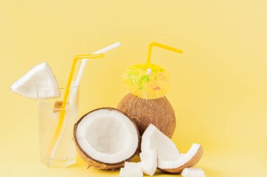 Sarı arka planda bir pipet ile taze Hindistan cevizi kokteyli