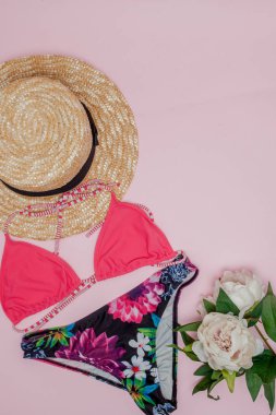 Şapka, pembe arka planda mayo ve güneş gözlüğü. Üst görünüm, düz yatıyordu, metin için alan