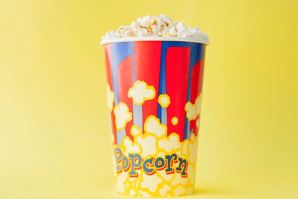 Popcorn in einem rot-weißen Karton auf gelbem Hintergrund. Kopierraum. flache Lage — Stockfoto
