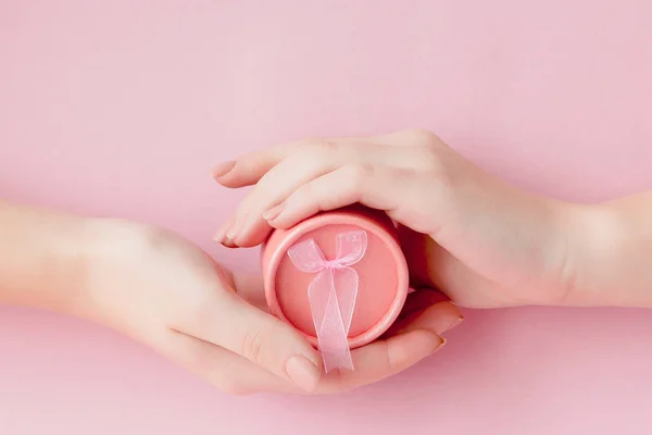 Okrągłe pudełko różowy w kobiet ręce na różowym tle. Koncepcja uroczysty Valentine's day, dzień matki lub urodziny — Zdjęcie stockowe