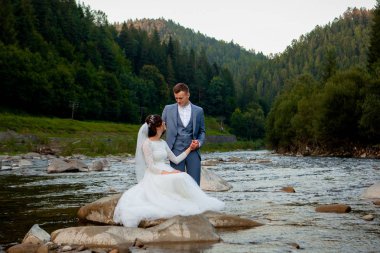 Ayakta ve nehrin üzerinde gülümseyen mutlu yeni evliler. Balayı, Sevgililer günü için fotoğraf