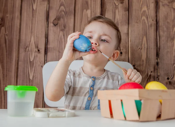 Küçük çocuk renkli yumurta Paskalya için ahşap arka plan üzerinde boyama