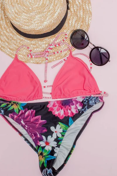 Şapka, pembe arka planda mayo ve güneş gözlüğü. Üst görünüm, düz yatıyordu, metin için alan