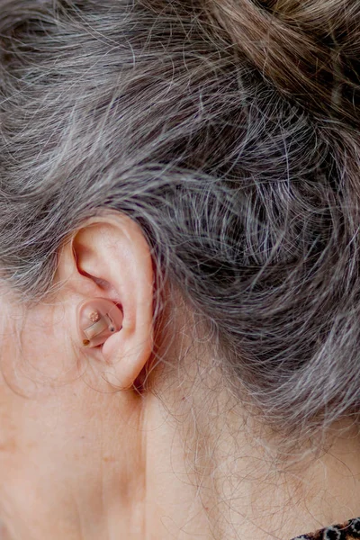 Senior vrouw close-up gehoorapparaat in haar oren invoegen — Stockfoto