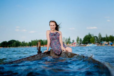 Büyük bir Svityaz gölünde, eski ahşap bir teknede oturan kadın. Yaz kavramı.