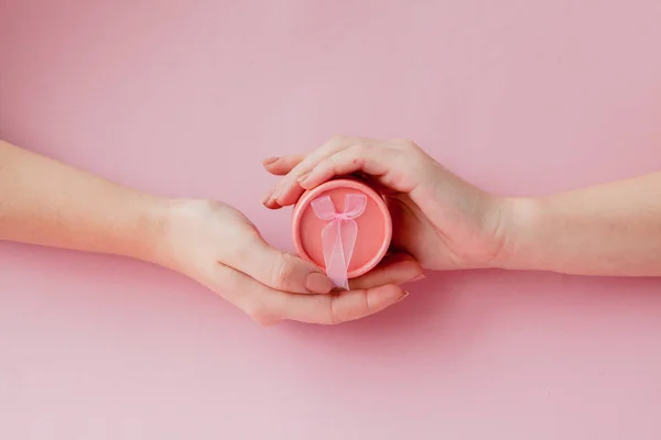Okrągłe pudełko różowy w kobiet ręce na różowym tle. Koncepcja uroczysty Valentine's day, dzień matki lub urodziny — Zdjęcie stockowe