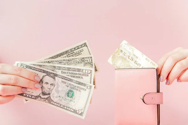 Kiev, Oekraïne - 22 februari 2019: Dollars en roze portemonnee met credit card in handen van de vrouw op roze achtergrond — Stockfoto