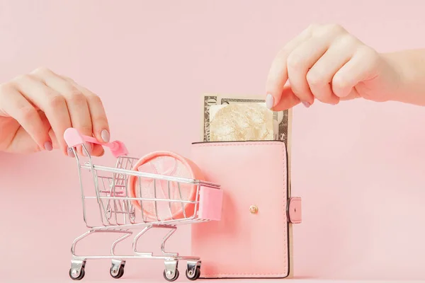 Dolary, pudełko na prezent i różowy portfel z kartą kredytową w rękach kobiety na różowym tle. — Zdjęcie stockowe